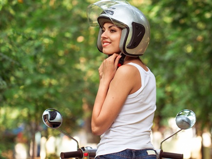 Attractive woman riding on a moped wearing helmet